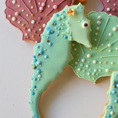 decorated cookies with seahorses and leaves on top of each other in pastel colors