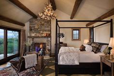 a bedroom with a bed, chair and fireplace in the corner next to two windows