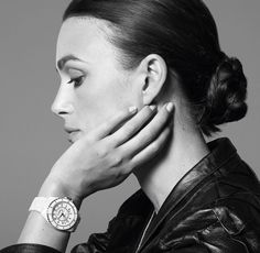 a woman with her hand on her face, wearing a watch and black leather jacket