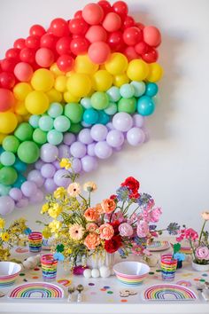 a table topped with lots of colorful balloons and vases filled with flowers on top of it