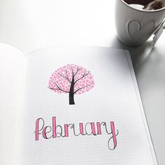 an open notebook with the word february written in pink on it next to a cup of coffee