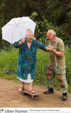 an older woman holding an umbrella and standing next to a man on a skateboard