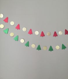 a string of christmas trees is hanging on the wall with confetti around them