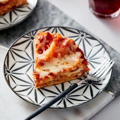 a slice of pizza on a plate with a fork and glass of wine in the background