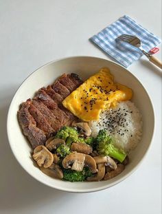 a white bowl filled with meat, mushrooms and broccoli on top of rice