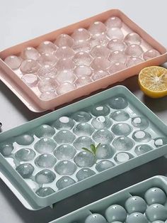 three trays filled with ice cubes and lemon slices on top of a table