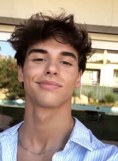 a close up of a person wearing a shirt and smiling at the camera with a building in the background