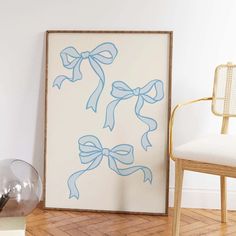 a white chair sitting next to a painting with blue bows hanging on it's side