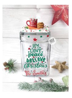 a glass jar filled with christmas treats on top of a white wooden table next to a star