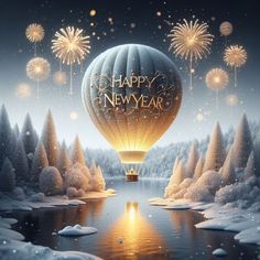 a hot air balloon flying over a lake surrounded by snow covered trees and sparklers