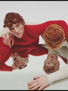 three people in red sweaters are looking at each other with their hands on the ground