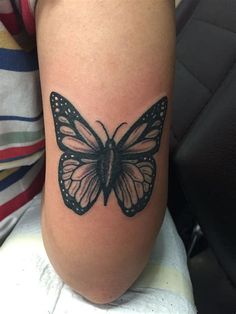 a black and white butterfly tattoo on the leg by a woman's arm,