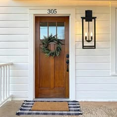 a front door with a wreath on it and two lights hanging from the side wall