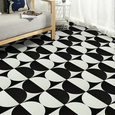 a black and white geometric rug in a living room with a couch, coffee table and window