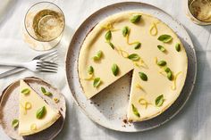 a cheesecake on a plate next to two glasses and silverware with one slice missing