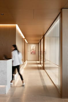 a blurry photo of a woman walking down a long hallway in a modern building