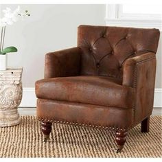 a brown leather chair sitting on top of a rug next to a vase with flowers