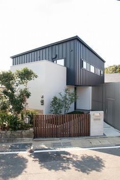 a modern house with black and white sidings on the front, fenced in area next to it