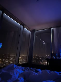 a bedroom with a view of the city lights at night from it's windows