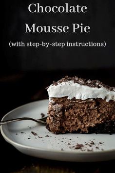 a piece of cake on a white plate with a fork in the foreground and a dark background