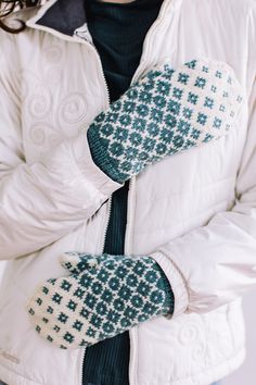 a woman in white jacket and blue mittens holding her hands out to the side