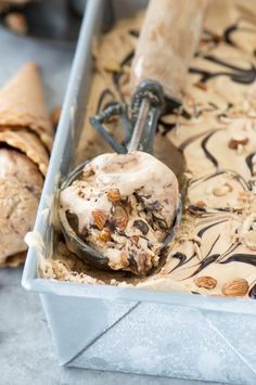 an ice cream sundae in a metal container with a scoop full of ice cream