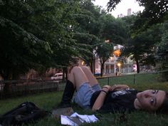 a woman laying in the grass with her legs spread out and head on her back