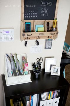 a black desk with some books and office supplies on top of it next to a chalkboard