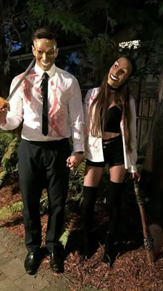 a man and woman dressed up as zombies holding hands while standing next to each other