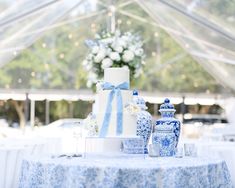 a blue and white cake sitting on top of a table next to two vases