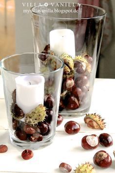 two glass vases filled with different types of fruit and candles on a white table