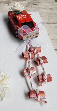 a red toy car sitting on top of a piece of paper next to white flowers