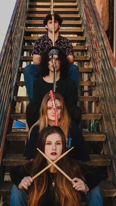 three women sitting on stairs with sticks sticking out of their heads and looking at the camera