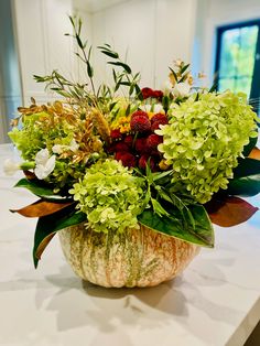 a vase filled with lots of flowers sitting on top of a white marble countertop