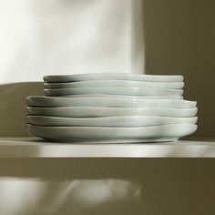 a stack of white plates sitting on top of a shelf