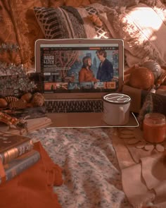 an open laptop computer sitting on top of a bed covered in blankets and other items