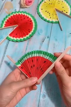 someone is holding a paper fan with watermelon slices on it and other decorations