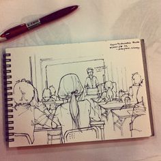 an open notebook with a drawing of people sitting at desks in front of them