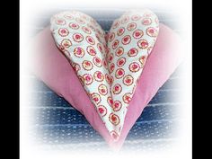 a pink and white heart shaped pillow sitting on top of a blue tablecloth covered surface