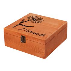 a wooden box with an engraved flower on the lid and name written in black ink