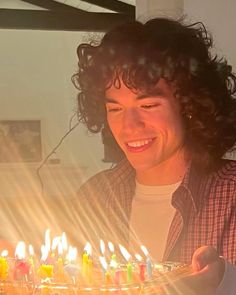 a man holding a birthday cake with lit candles