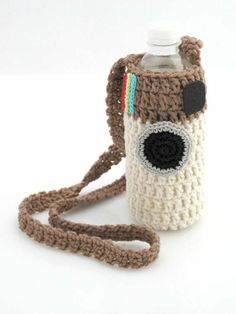 a crocheted camera bag with a water bottle in the front and strap around it