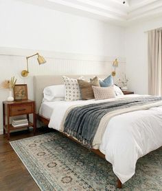 a bedroom with a bed, rug and two lamps on the side of the room