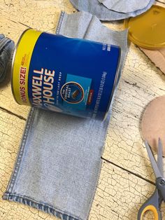 a pair of scissors sitting on top of a blue cloth next to a can of paint