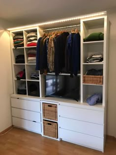 a white closet with clothes and baskets on it