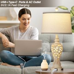 a woman is sitting on the couch with her laptop in front of her, which is plugged into an outlet