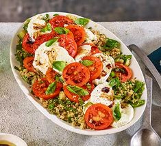 a salad with tomatoes and mozzarella in a white bowl on top of a table