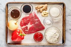 a tray with meat, cheese, tomatoes and other ingredients on it next to an apple