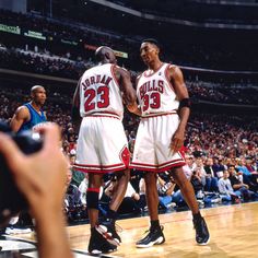 two basketball players standing next to each other in front of an arena full of people