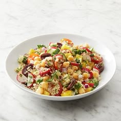 a white bowl filled with salad on top of a marble counter